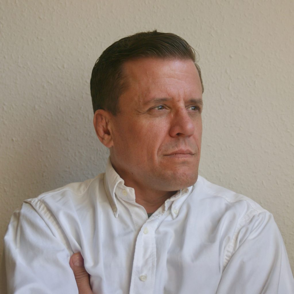 Pol is a caucasian man with mid brown hair and brown eyes. He is wearing a white shirt.